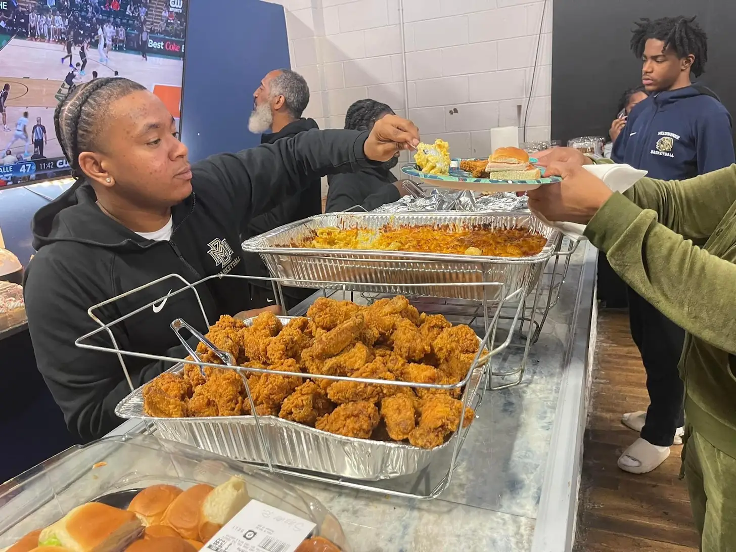 People serving and grabbing food at an event