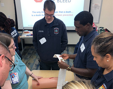 people gathered around medical tools to demonstrate how to stop bleeding